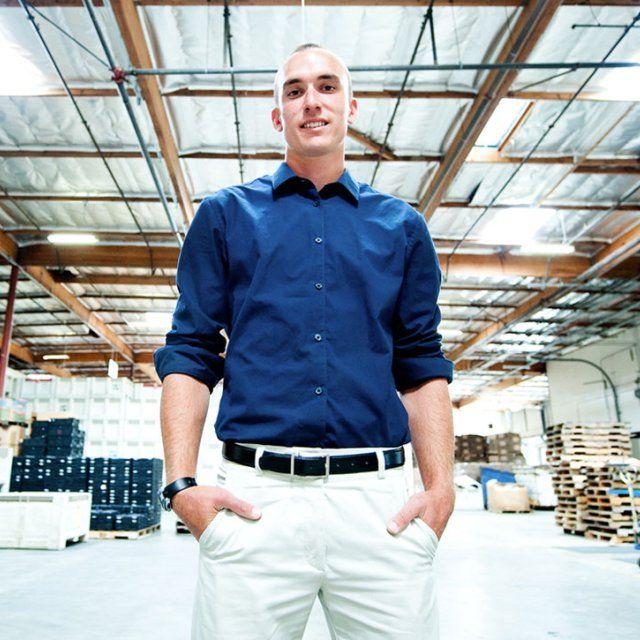 一个穿着蓝屎白裤子的人双手插在口袋里站在仓库里